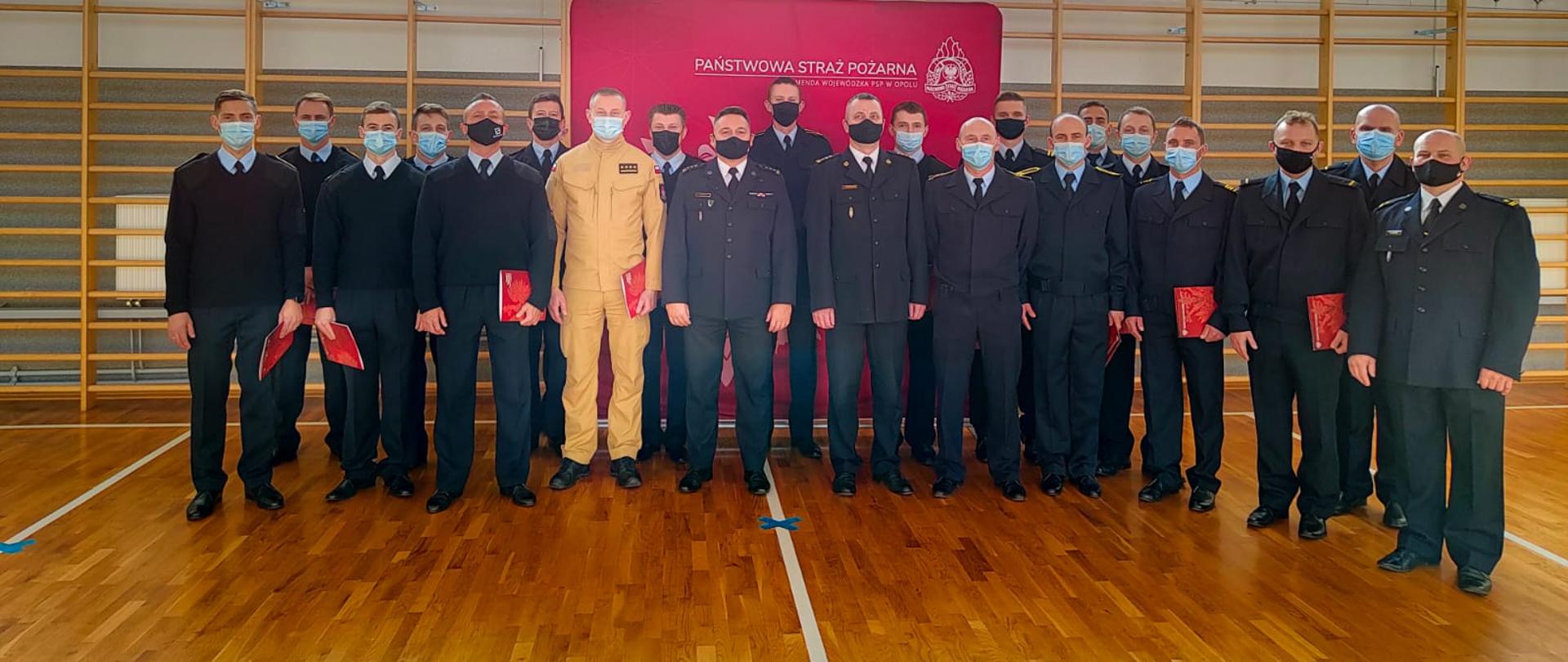 Grupa funkcjonariuszy PSP w sali gimnastycznej podczas wręczenia podziękowań