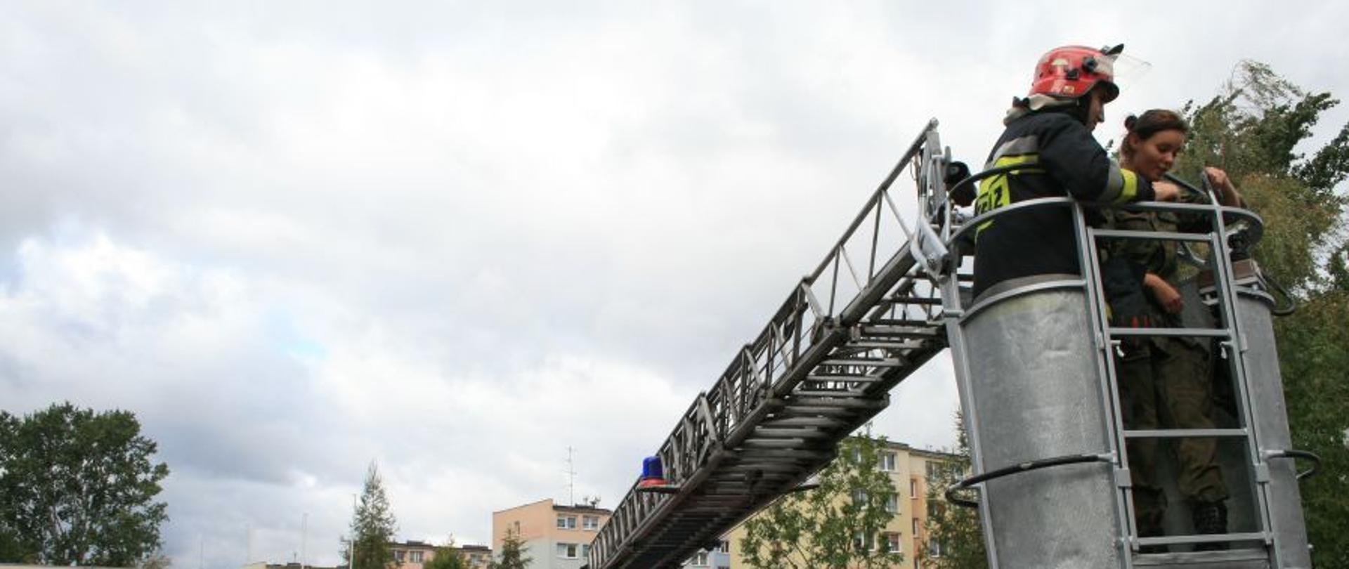 Strażak z dziewczyną w koszu drabiny mechanicznej