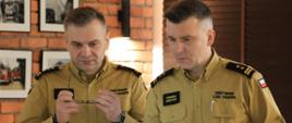 Narada roczna w Komendzie Powiatowej PSP w Mońkach - komendanci - wojewódzki i powiatowy patrzą w ekran laptopa