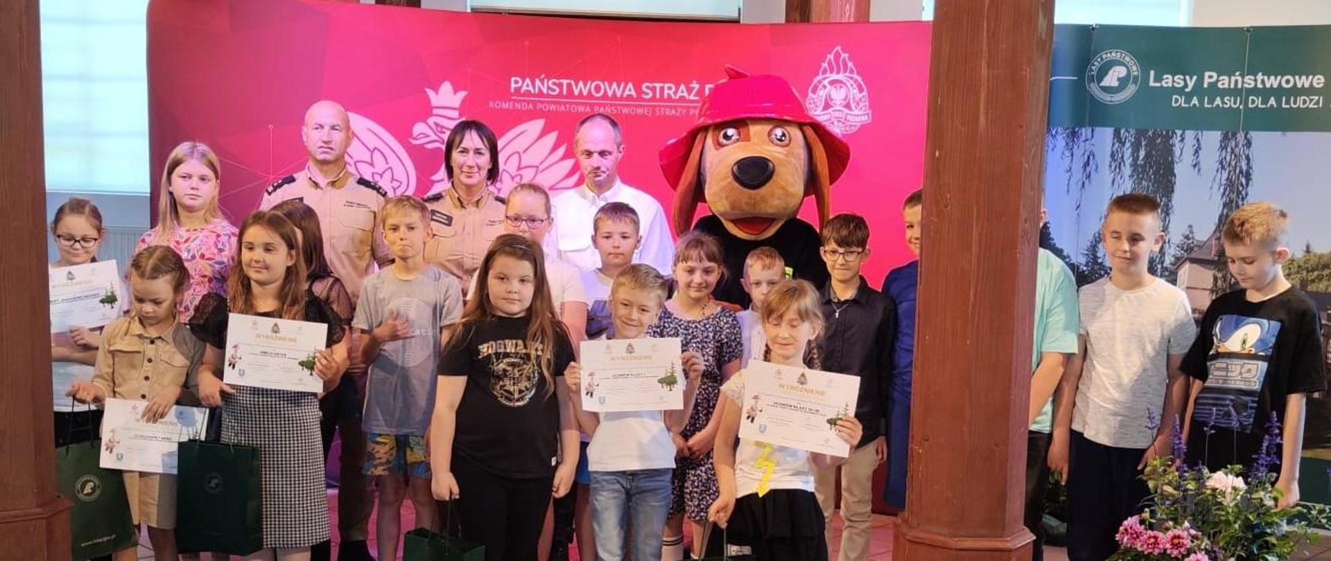 Dwóch mężczyzn oraz kobieta podczas wręczenia dyplomów uczestnikom konkursu.