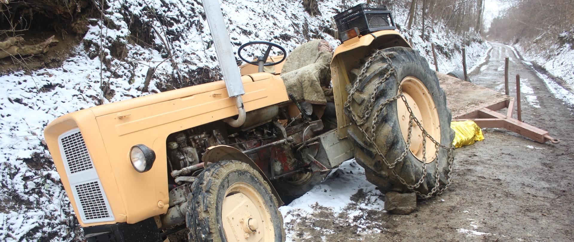 Zdjęcie przedstawia ciągnik rolniczy marki Ursus C-360 stojący w przydrożnym rowie przechylony na swoją lewą stronę