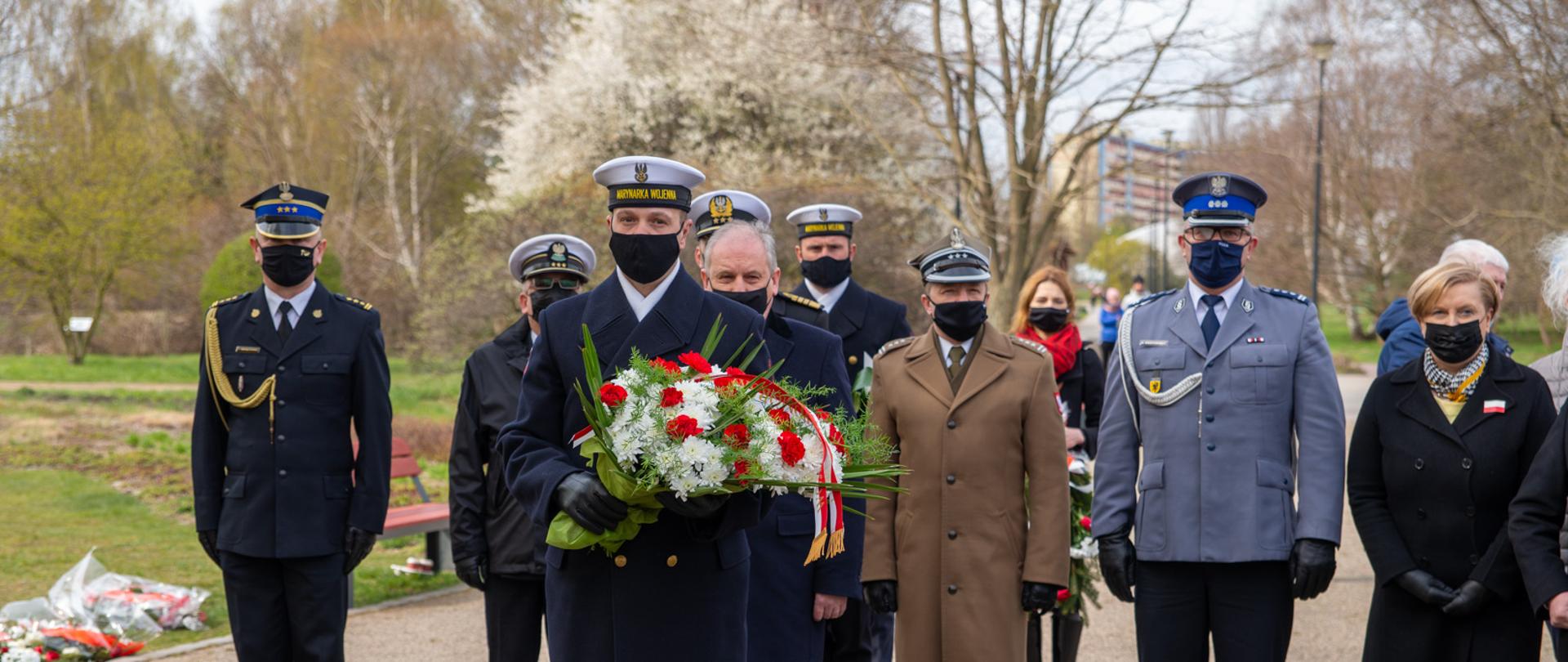 Przedstawiciele służb mundurowych składają wieniec.