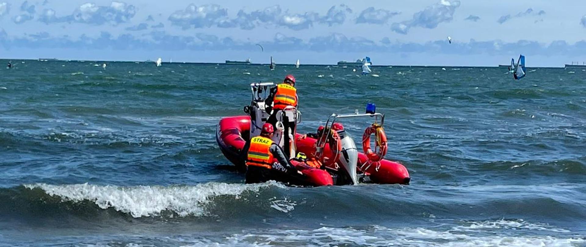 Zatoka Gdańska, spienione fale przy brzegu a na nich unosząca się łódź pontonowa na której znajdują się ratownicy WOPR i strażacy. Łódź skierowana do wypłynięcia w stronę morza.