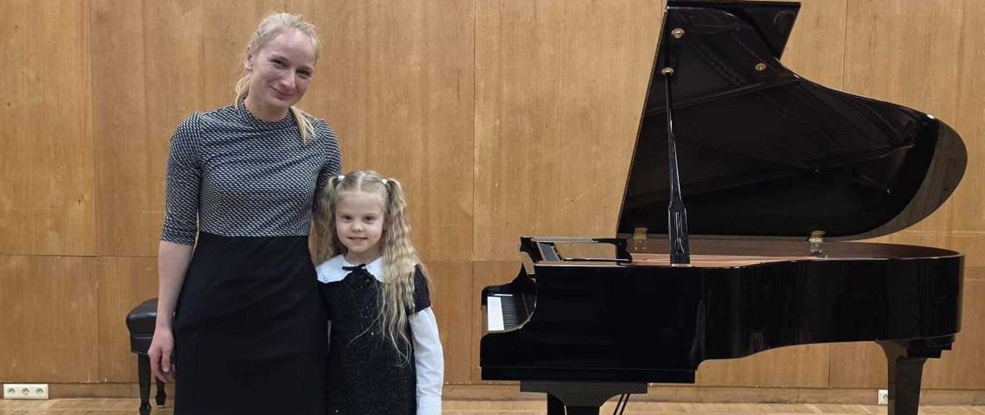 Klara Utrata i Jagoda Młynarska pozują do zdjęcia na scenie. W tle fortepian.