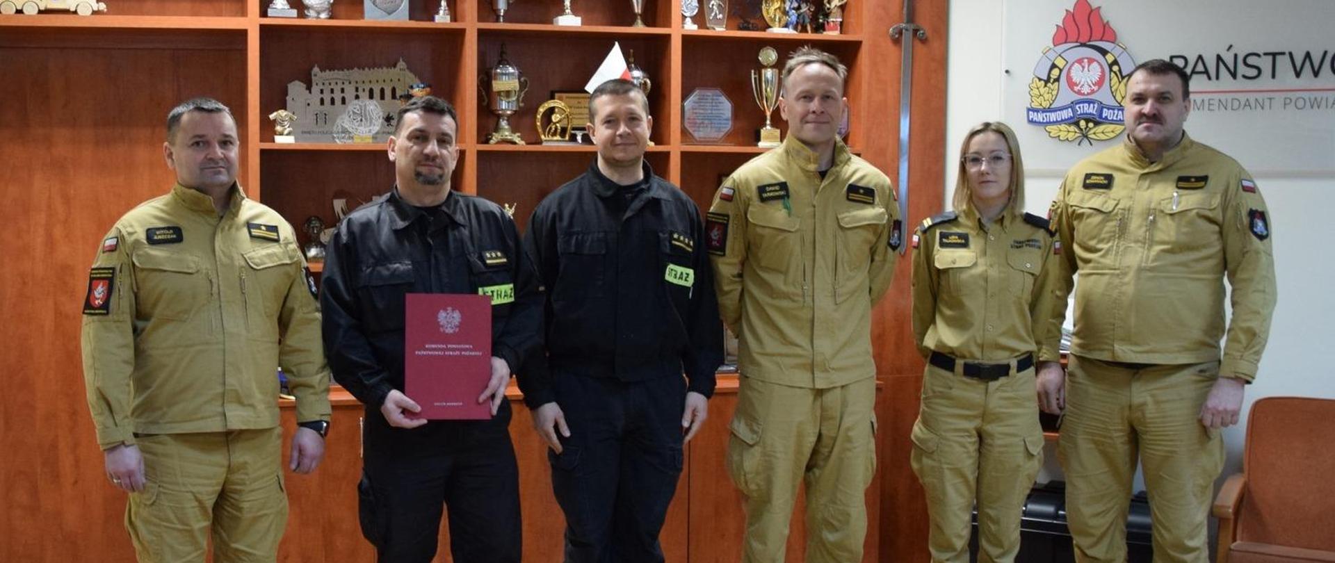 Funkcjonariusz obchodzący jubileusz 25-lecia służby i pracy kpt. Dariusz Kuciński stoi w szeregu z funkcjonariuszami obecnymi podczas wręczenia nagrody jubileuszowej.