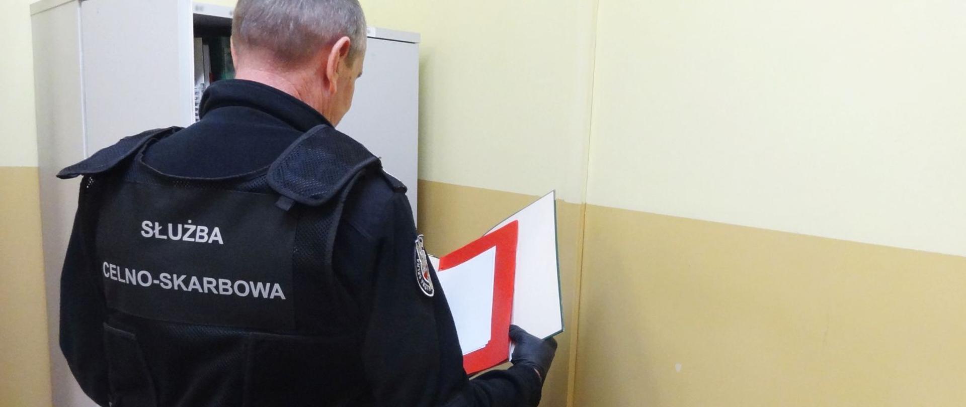 Funkcjonariusz Służby Celno-Skarbowej KAS podczas przeglądania dokumentacji.