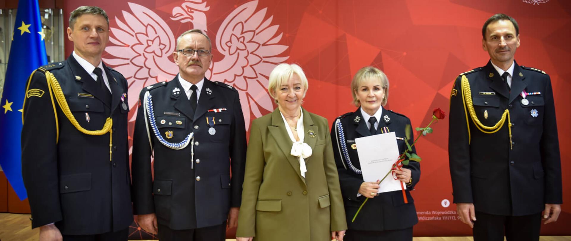 Na zdjęciu widzimy Komendanta Wojewódzkiego Państwowej Straży Pożarnej w Łodzi st. bryg. Marcina Dulasa, Wojewodę Łódzkiego Panią Dorotę, Komendanta Powiatowego Państwowej Straży Pożarnej w Sieradzu st. bryg. Radosława Jadwiszczaka oraz druha Mirosława Frankiewicza podczas uroczystej zbiórki. 