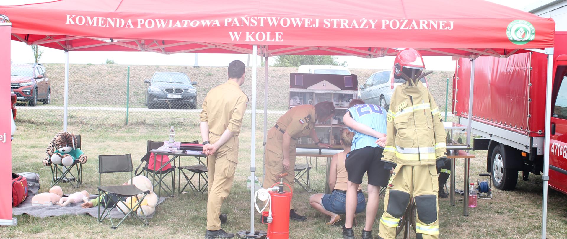Zdjęcie przedstawia strażaków oraz dzieci i dorosłych podczas festynu rodzinnego w Dąbiu