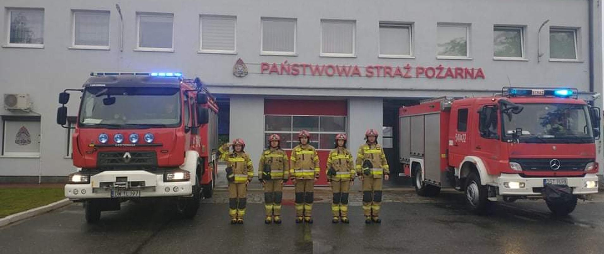 Strażacy stoją prze budynkiem komendy