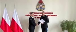 Na zdjęciu Zachodniopomorski Komendant Wojewódzki PSP nadbryg. Jarosław Tomczyk, który wręcza akt powołania kpt. Marcinowi Zięcinie na stanowisko Zastępcy Komendanta Powiatowego PSP w Pyrzycach. Po lewej na stojaku dwie biało-czerwone flagi.