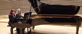 Uczennica z Panią Iwoną Ulbrich grające na fortepianie na scenie sali koncertowej PSM