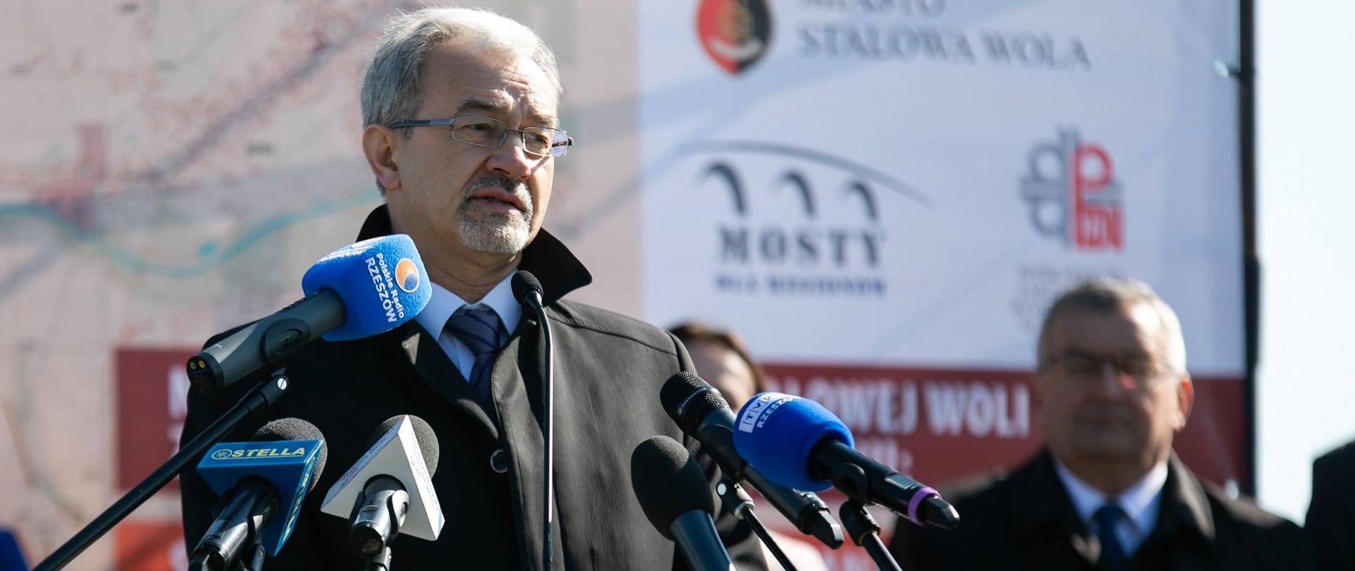 Minister Jerzy Kwieciński podczas konferencji prasowej przemawia do stojących przed nim mikrofonów