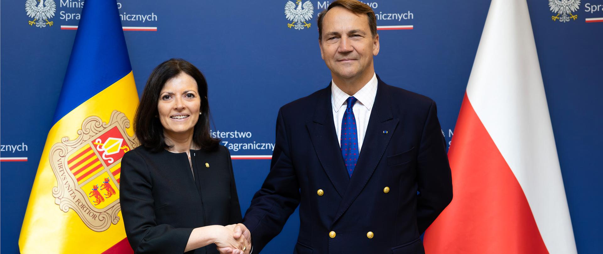 Wicepremier, Minister Spraw Zagranicznych Radosław Sikorski i szefowa dyplomacji Andory Imma Tor Faus ściskający sobie dłonie dla tle flag obu państw.