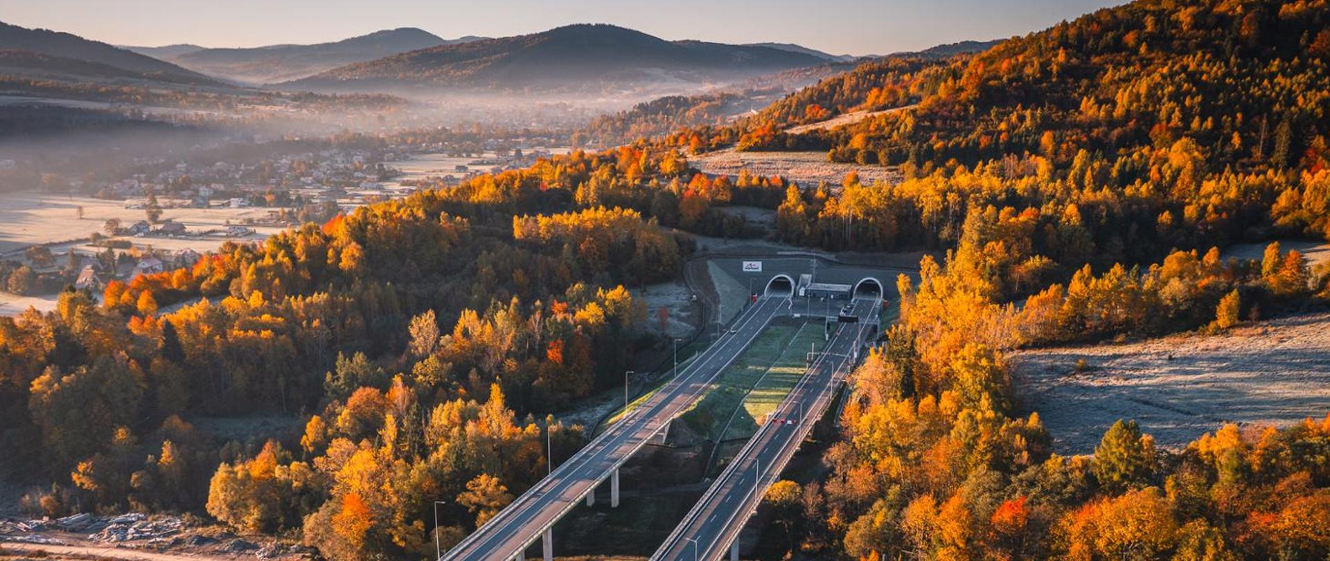 Zdjęcie przedstawia drogę ekspresową prowadzącą przez tunel. Krajobraz jesienny.