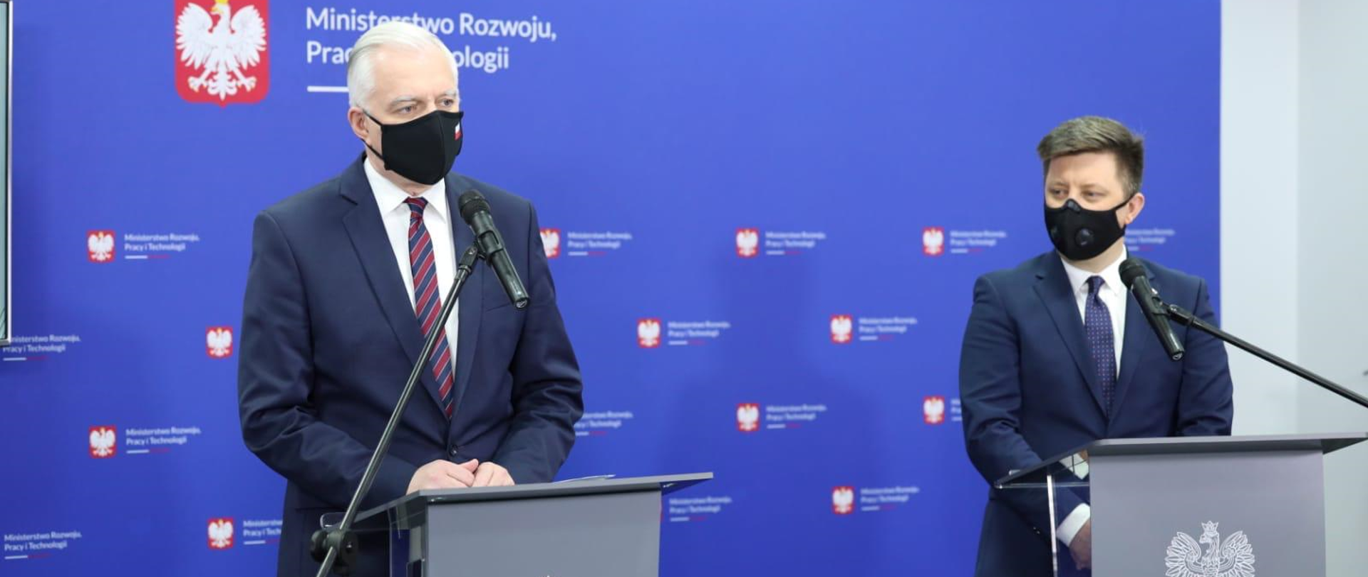 Konferencja prasowa wicepremiera J. Gowina i min. M. Dworczyka na niebieskim tle.