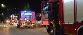 Ustawione w szeregu cztery samochody strażackie na drodze w pobliżu miejsca pożaru
