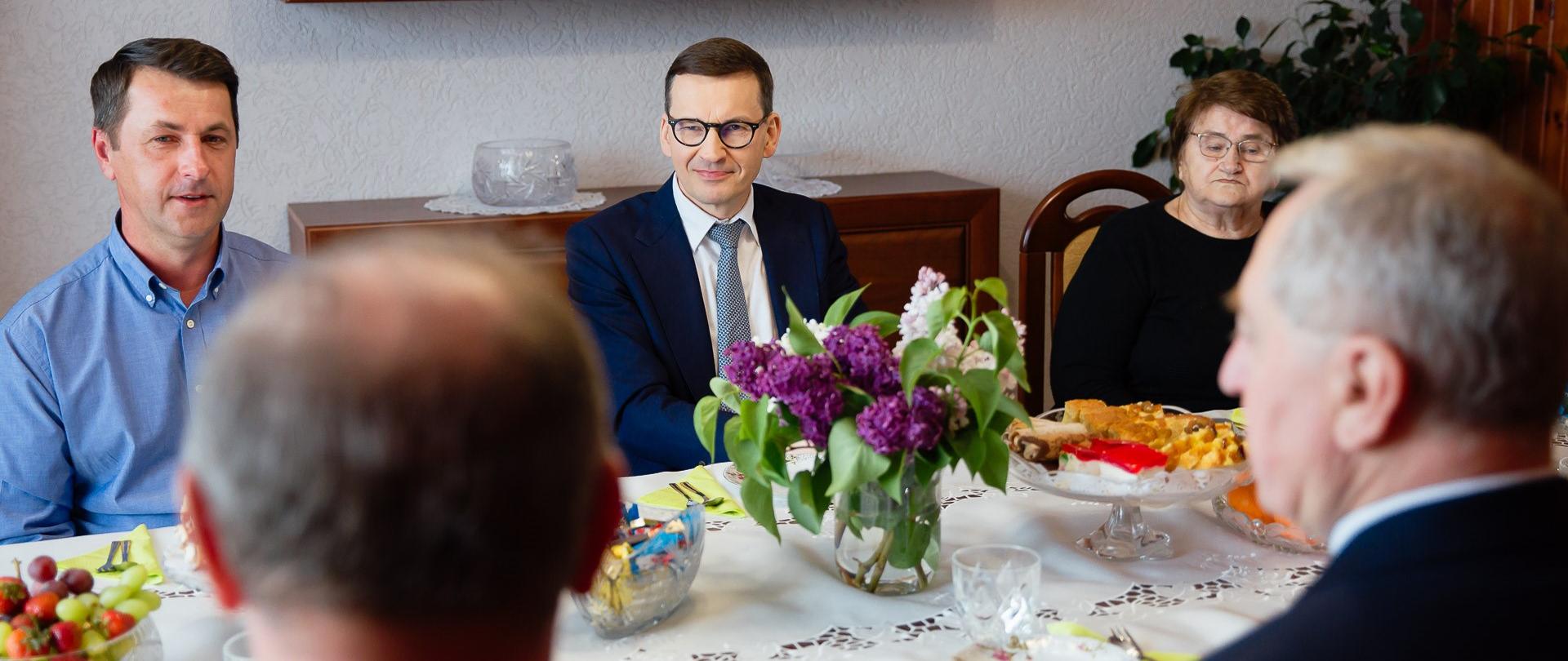 Premier siedzi przy stole.