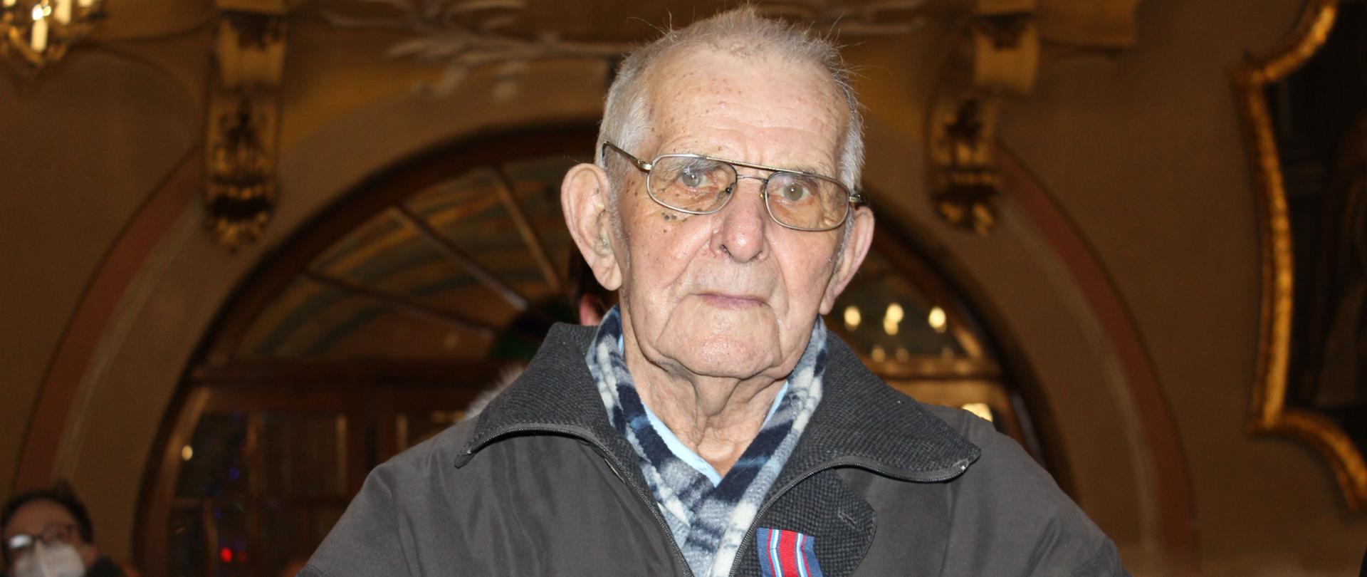 Widok z przodu - półzbliżenie. Jubilat z przypiętym na piersi odznaczeniem.