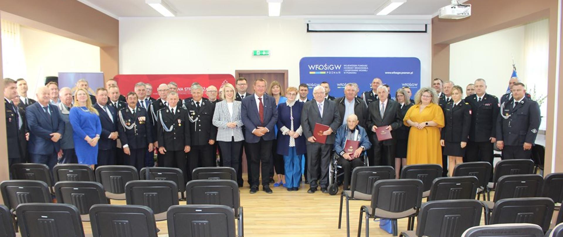 Na zdjęciu widoczna jest uroczystość związana z podpisaniem umów o dotację z Wojewódzkiego Funduszu Ochrony Środowiska i Gospodarki Wodnej w Poznaniu. Uroczystość odbyła się wewnątrz pomieszczenia, jest dzień. 