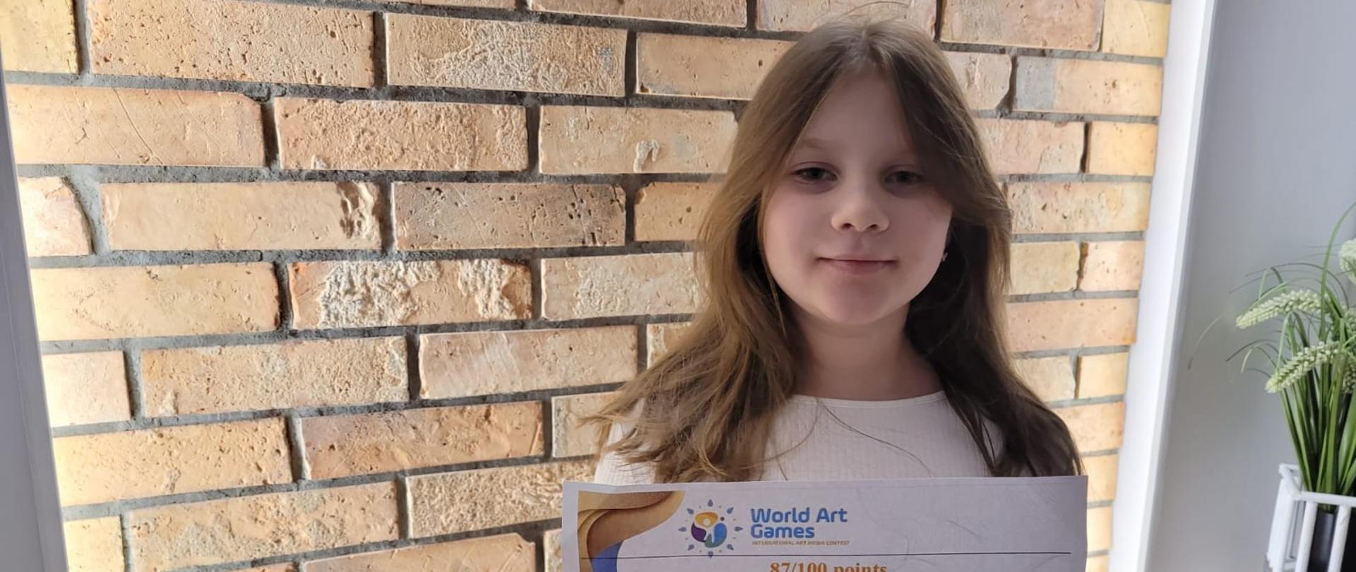 Uczennica ZPSM z dyplomem na tle ściany z cegły