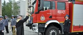 Zdjęcie przedstawia moment poświęcenia nowego samochodu ratowniczo-gaśniczego przez ks. Dziekana Krzysztofa Kiełbowicza. 
