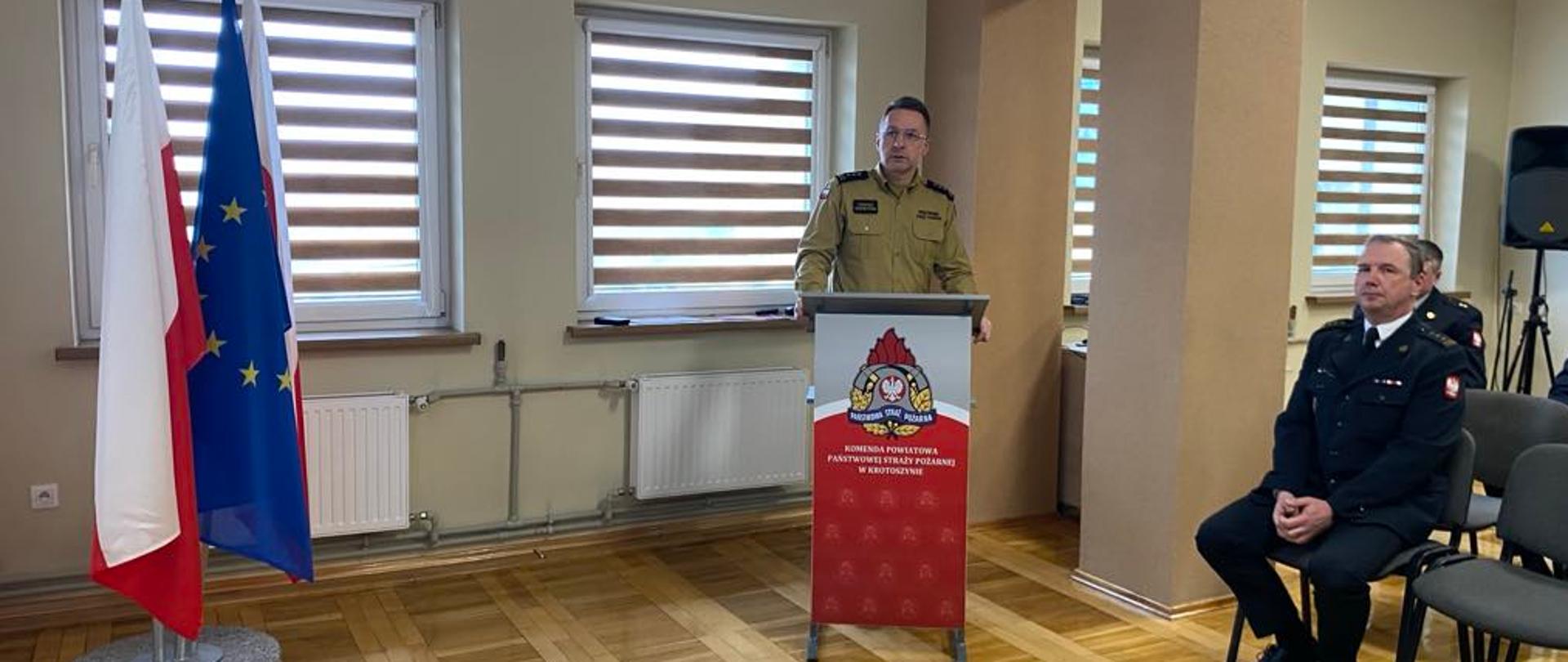 Zdjęcie przedstawia Funkcjonariusza Państwowej Straży Pożarnej podczas wystąpienia okolicznościowego. 