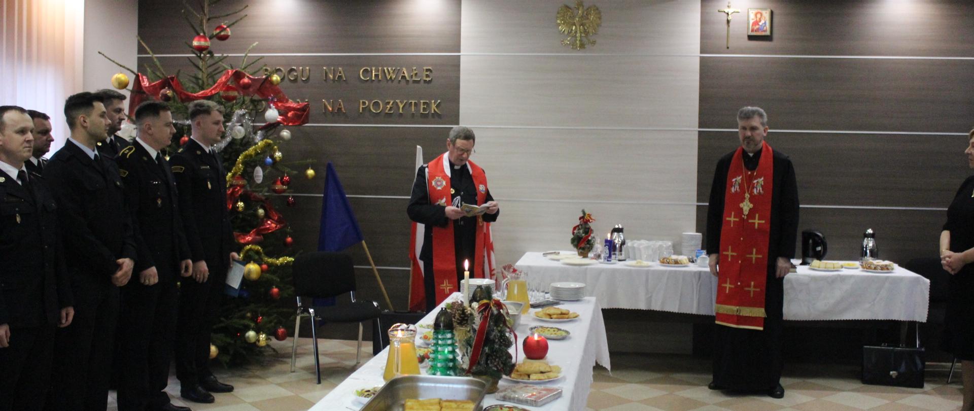 Zdjęcie przedstawia księży i funkcjonariuszy straży pożarnej podczas modlitwy