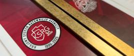 Na dyplomie w złotej ramce widoczne logo Krajowego Systemu Ratowniczo-Gaśniczego. 