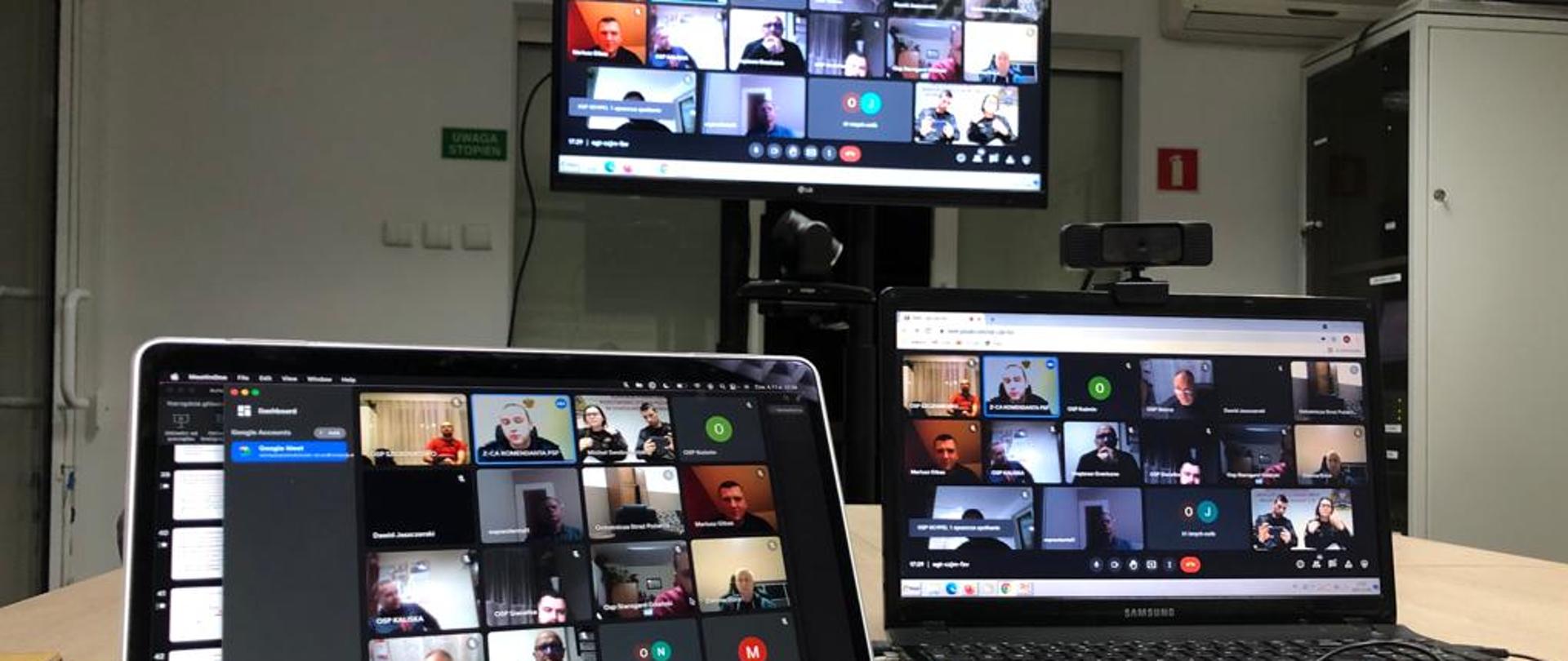 Zdjęcie przedstawia try pulpity komputerowe, z widokiem uczestników wideokonferencji. Na pierwszym planie myszka komputerowa i mikrofon, w tle stojak ze sprzętem do wideokonferencji