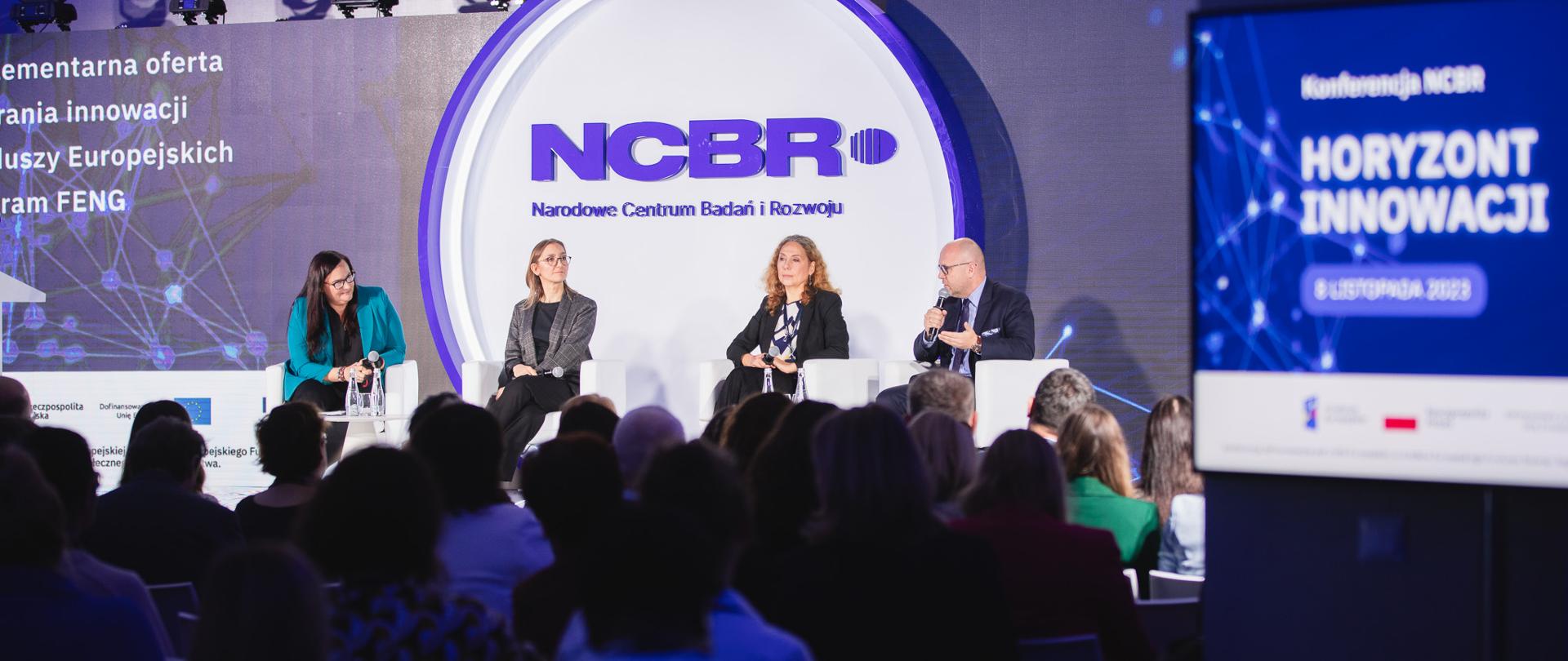 Wiceminister funduszy i polityki regionalnej Małgorzata Jarosińska-Jedynak prowadzi dyskusję w panelu „Komplementarna oferta wspierania innowacji z Funduszy Europejskich – z programu #FENG” - uczestnicy debaty siedzą na scenie 