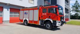 Zdjęcie przedstawia nowy ciężki samochód ratowniczo - gaśniczy, który stoi na placu przed budynkiem komendy 
