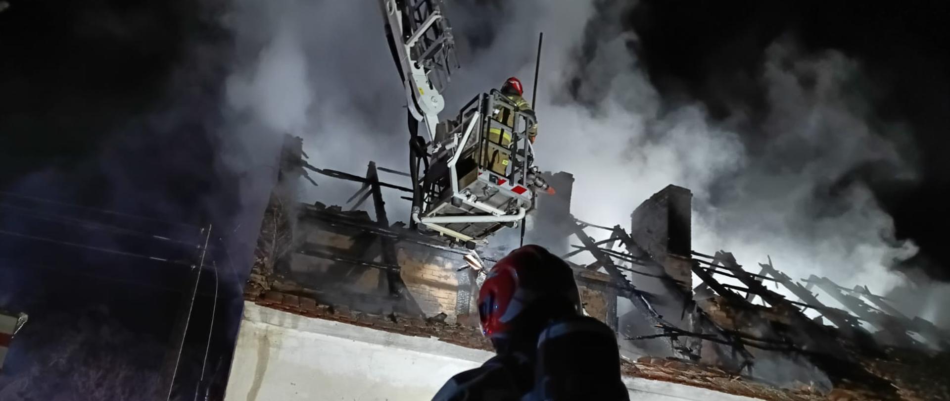 Strażacy w podnośniku gaszący dach budynku