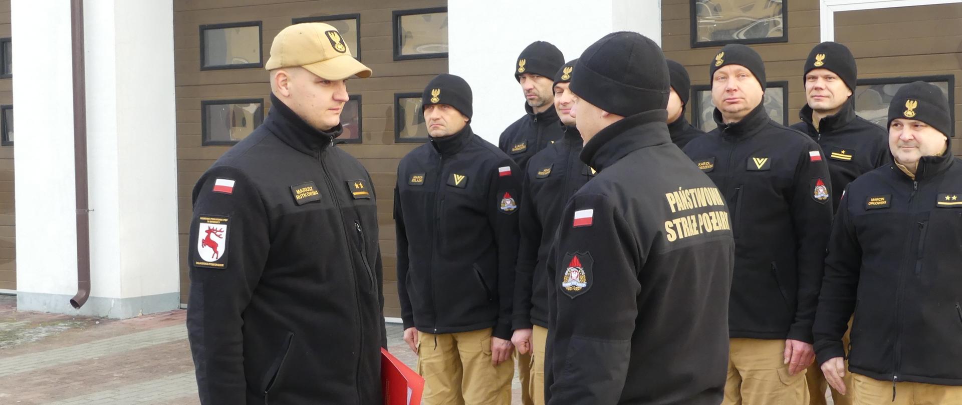 Zdjęcie podczas uroczystej zbiórki, Na zdjęciu st. kpt. mgr Krzysztof Natucki Komendant Powiatowy PSP w Brodnicy wręcza mł. kpt. Mariuszowi Rutkowskiemu decyzję o mianowaniu na stanowisko zastępcy dowódcy zmiany.